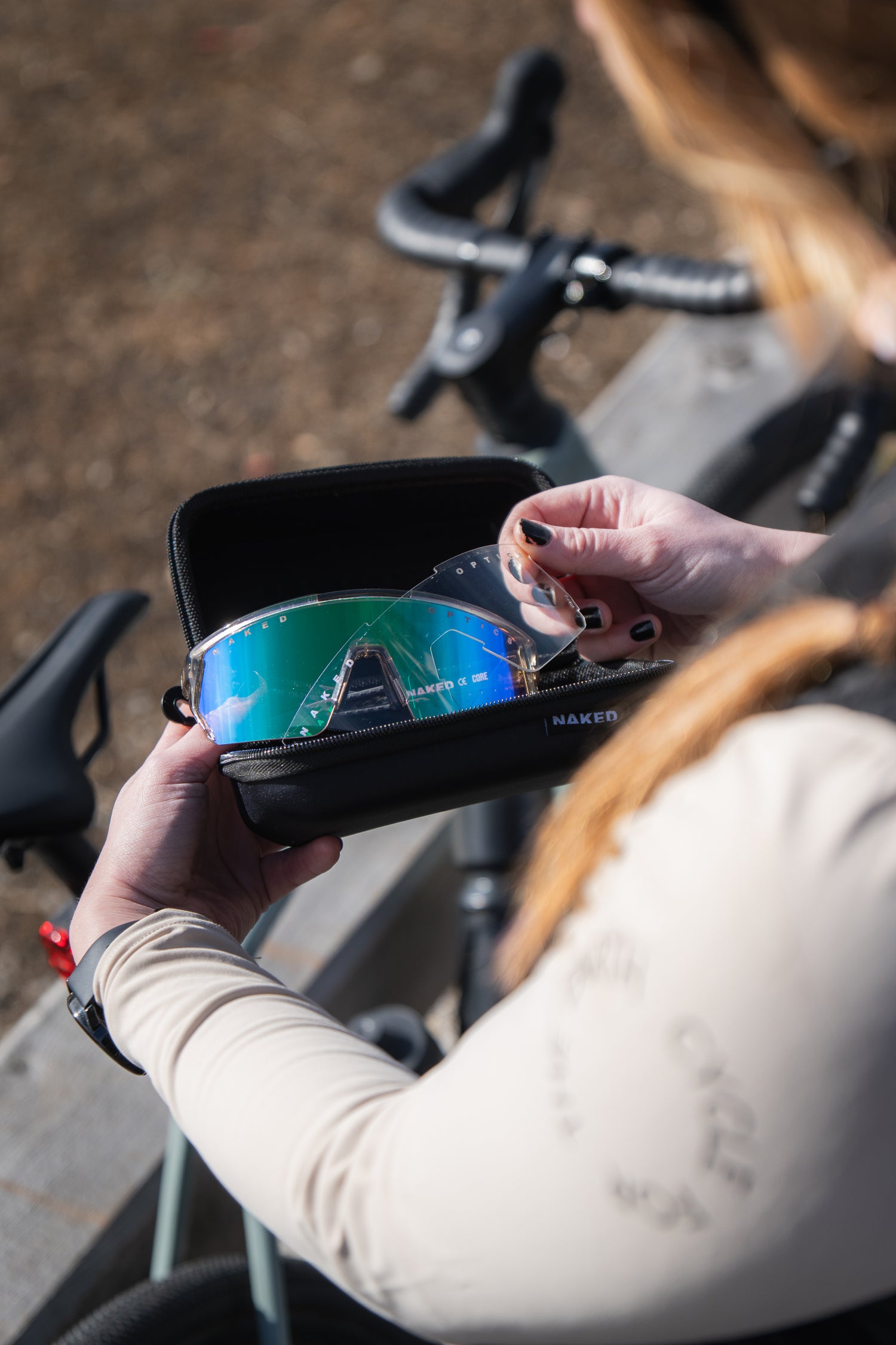 Eine Fahrradfahrerin hält ein Etui mit einer Sportbrille und einem passendem klaren Wechselglas in der Hand; Credits: Elias Neier