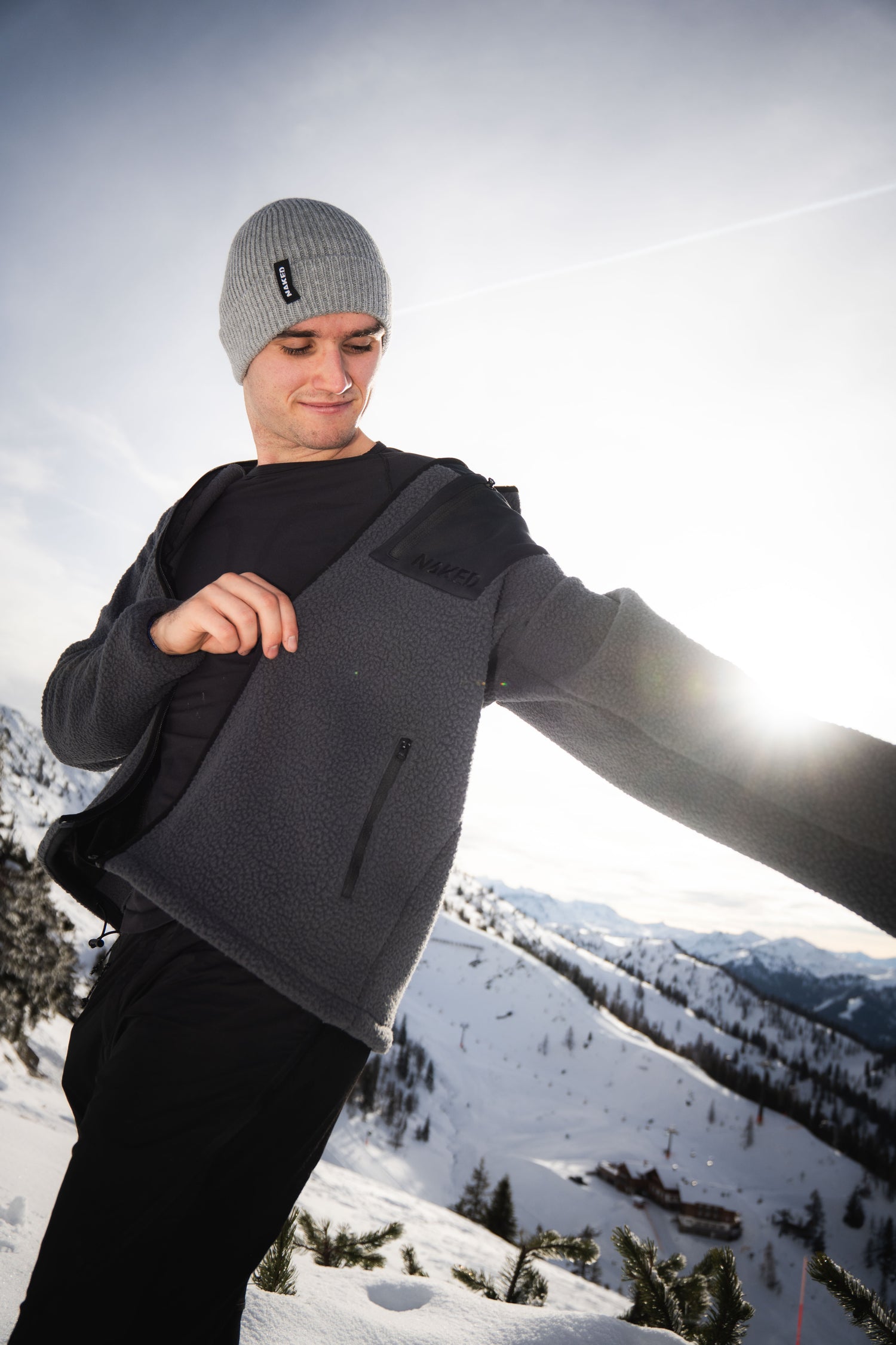 Ein Mann zieht sich am Berg seine warme Fleecejacke an; Credits: Elias Neier