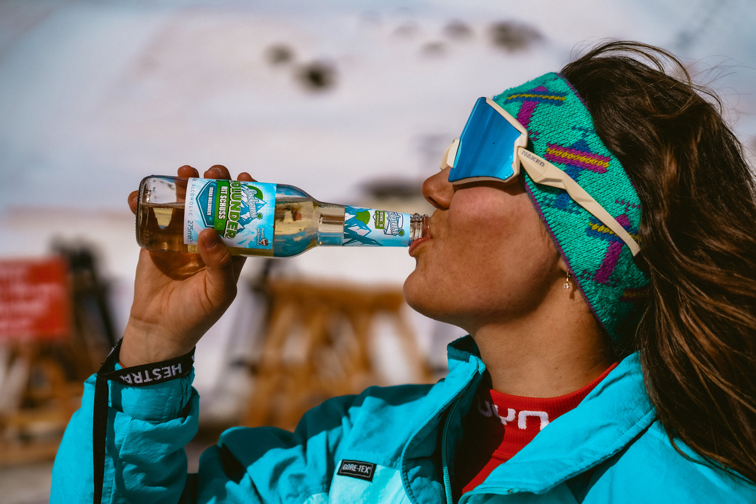Eine Frau trinkt aus einer Flasche und schaut in die Sonne, ihre Augen werden von einer schnellen Brille geschützt; Credits: Retro Rebels